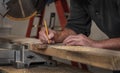 Closeup carpenter marking measurement on wood board with old wooden handle square and pencil