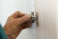 Closeup of carpenter`s hands fitting wardrobe hinge doors in walk-in closet. Royalty Free Stock Photo
