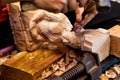 Closeup of a carpenter`s hands working with a chisel and hammer on wooden buddha sculpture