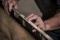 Closeup of carpenter`s rough rugged hands using old level tool on edge of wood board