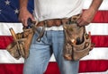 Closeup carpenter wearing old, worn out leather toolbelt in front of American flag Royalty Free Stock Photo