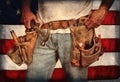 Closeup carpenter wearing old, worn out leather toolbelt in front of American flag Royalty Free Stock Photo