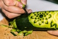 Closeup carved cucumber with the hand and carving knife