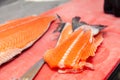 Closeup carving whole fresh norwegian salmon fish with knife on red cutting board in professional kitchen restaurant, preparing Royalty Free Stock Photo