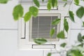 Closeup cassette Air Conditioner on ceiling in modern light office or apartment with green ficus plant leaves. Indoor