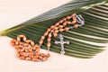 Closeup Catholic rosary with crucifix and beads on palm leaf