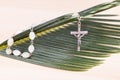 Closeup Catholic rosary with crucifix and beads on palm leaf