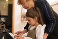 Closeup charming little child girl sitting at piano while a female teacher pianist teacher giving music lesson at home