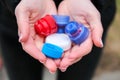 Closeup at caucasian female hands full of colorful plastic bottle cups, handful of waste of plastic lids. Recycling. Collecting Royalty Free Stock Photo