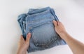 Closeup caucasian female hands holding three pairs of blue denim jeans. Isolated on white background