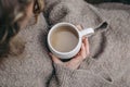 Closeup of caucasian girl, child in beige knitted sweater holding white ceramic spotted cup of coffee. Autumn cozy