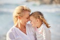 Closeup of a caucasian girl laughing while enjoying a day out with her mother at the beach. Mom and daughter enjoying a Royalty Free Stock Photo