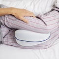 Man in bed using an anatomical leg cushion