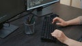 Closeup of caucasian programer hands typing code on keyboard in front of computer screens