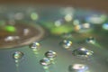 Closeup of a CD with water drops on it on the table under the lights with a blurry background Royalty Free Stock Photo