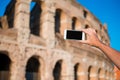 Closeup cell phone in front of Colosseum in Rome, Italy