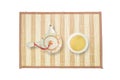 Closeup ceramic tea pot and tea cup with brown tea on wood mat isolated on white background