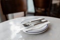 Closeup on ceramic two plates with stainless steel fork and knife prepared for dinner. Dishware with napkin and Royalty Free Stock Photo