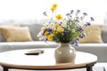 Closeup ceramic vase with wildflowers on round coffee table against background Royalty Free Stock Photo