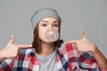 Closeup of cheeky teen girl blowing bubblegum and pointing at it