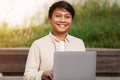 Closeup of cheerful asian guy using computer outdoors Royalty Free Stock Photo