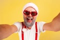 Closeup cheerful positive man in santa claus hat and stylish sunglasses looking into camera, posing making selfie Royalty Free Stock Photo