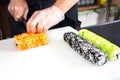 Closeup of chef hands rolling up sushi cuts into portions on kitchen