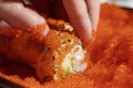 Closeup of chef hands rolling up sushi in flying fish roe (Tobiko) red caviar - focus on the roll. Royalty Free Stock Photo