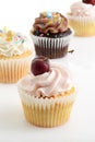 closeup cherry buttercream cupcake with assorted cupcakes in the background