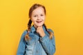 Closeup of a child in a denim shirt on a yellow background. Little girl smiles and looks at the camera Royalty Free Stock Photo