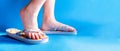 Closeup child feet wearing a pair of fun bright flip-flops on blue background. Kids and family lifestyle outdoors. The concept of Royalty Free Stock Photo