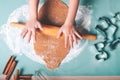 Closeup of child hands rolling fresh dough with a rolling pin on the table for Christmas gingerbread cookies in kitchen