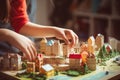 Closeup of child\'s hands arranging miniature town model with detailed buildings and trees