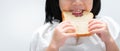 Closeup. Child`s hands holds the bread, kids teeth are bits chewing on the loaf of bread with gusto