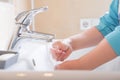 Closeup of a child`s soapy hands being washed under running water in a sink Royalty Free Stock Photo