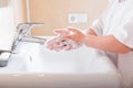 Closeup of a child`s soapy hands being washed under running water in a sink Royalty Free Stock Photo