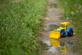 Closeup of children plastic toy tractor on a countryside road after rain. Nature background Royalty Free Stock Photo