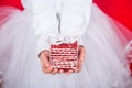 Closeup children`s hands holding festive red and white gift box.