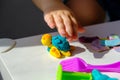 Closeup children`s hands with plasticine turtle on white table, children`s creative games at home with plasticine