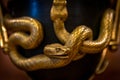 Closeup of chiseled and gilded snakes of old french bronze urn shaped clock at the Museum of Decorative Art