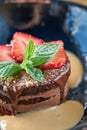 Closeup chocolate sponge cake, with caramel, decorated with strawberries and mint leaf. Breakfast in the cafe, morning Royalty Free Stock Photo