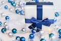 Closeup Christmas gift with blue ribbon and silver and blue Christmas balls and garland on white wooden background Royalty Free Stock Photo