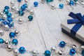 Closeup Christmas gift with blue ribbon and silver and blue Christmas balls and garland on white wooden background Royalty Free Stock Photo