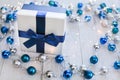 Closeup Christmas gift with blue ribbon and silver and blue Christmas balls and garland on white wooden background Royalty Free Stock Photo