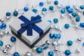 Closeup Christmas gift with blue ribbon and silver and blue Christmas balls on white wooden background Royalty Free Stock Photo