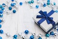 Closeup Christmas gift with blue ribbon and silver and blue Christmas balls on white wooden background Royalty Free Stock Photo