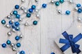 Closeup Christmas gift with blue ribbon and silver and blue Christmas balls and garland on white wooden background Royalty Free Stock Photo