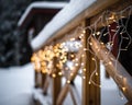 Closeup of Christmas lights on a wooden building covered in the snow on a blurry background Royalty Free Stock Photo