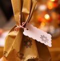 Closeup of Christmas present with stamp decorated wrapping paper and gift tag offering copy space. Golden colored bokeh lights. Royalty Free Stock Photo