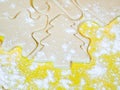 A closeup of a Christmas tree cutout and other holiday shapes in raw sugar cookie dough on a yellow cutting board with flour Royalty Free Stock Photo